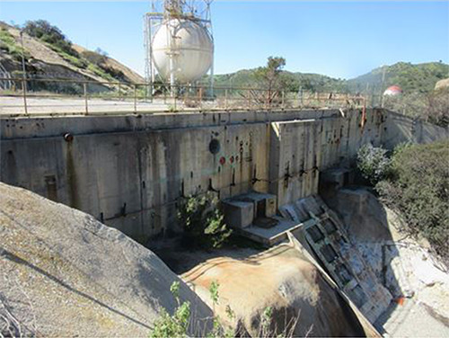 This photo shows large concrete slabbing and fencing, with a large white hydrogen tank in the background.